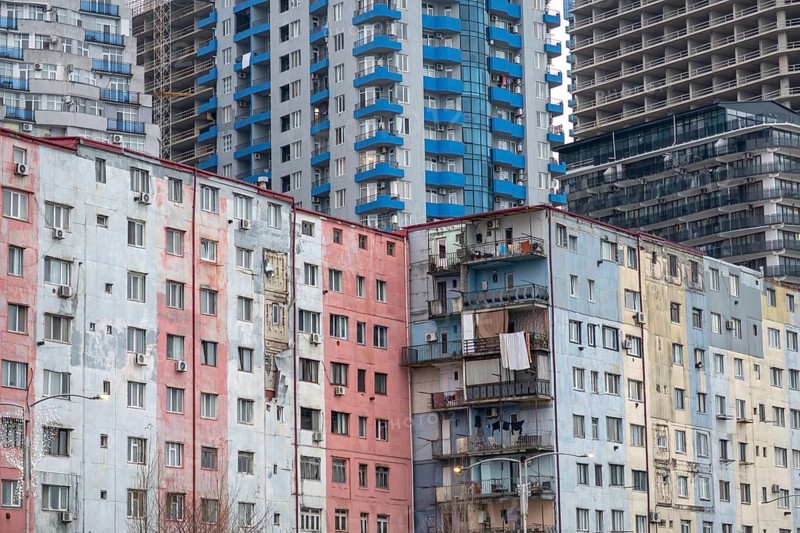A vibrant cityscape showcasing a mix of modern and older high-rise buildings with colorful facades, depicting urban life in a bustling area of Georgia