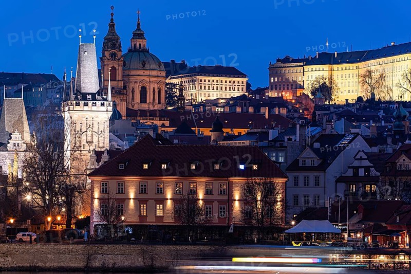 A beautiful evening shot of Prague featuring illuminated historical architecture and vibrant light trails on the riverfront, highlighting the city's rich cultural heritage
