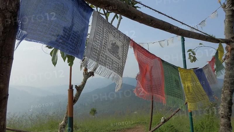 Colourful Buddhist prayer flags waving in the wind with a view of a mountainous landscape in the background, Sri Lanka
