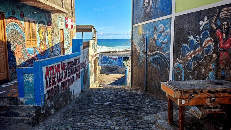 Narrow alley with many colorful wall paintings leading down to the sea, a table football, wooden soccer in the foreground, Cruzinha, hiking, Santo Antao, Cabo Verde, Cape Verde, Cape Verde