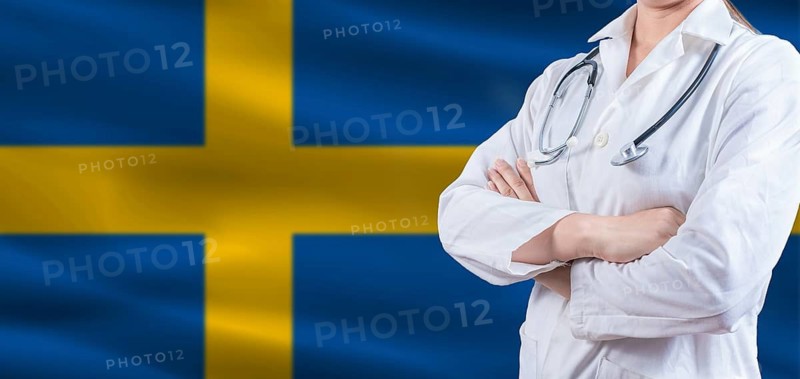 Doctor with crossed arms on Swedish flag. Sweden health and care concept. Female doctor on Swedish flag