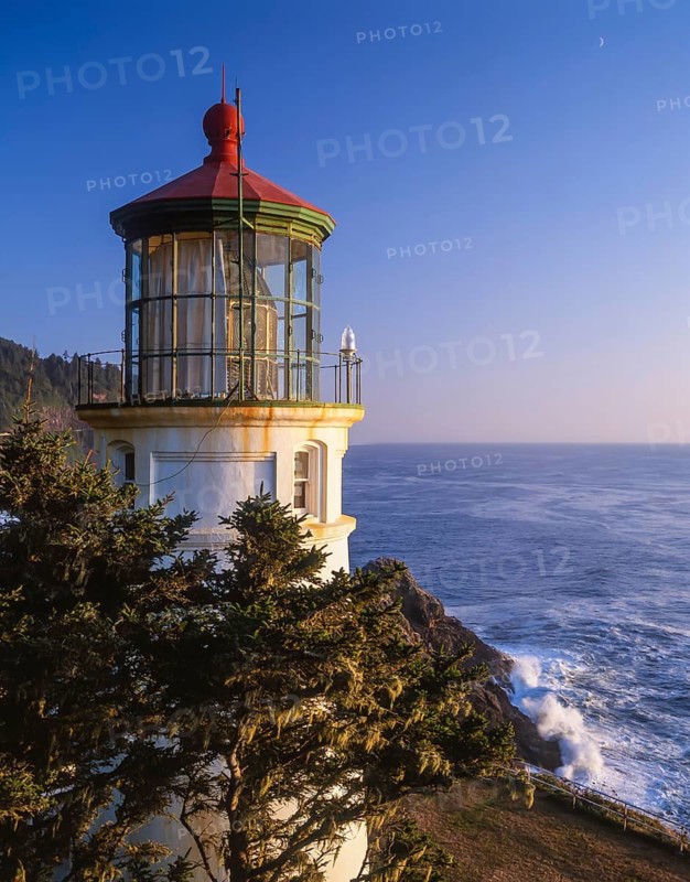 The Heceta Head Lighthouse stands majestically during dusk, its light casting a gentle glow over the Pacific Ocean along the Oregon Coast