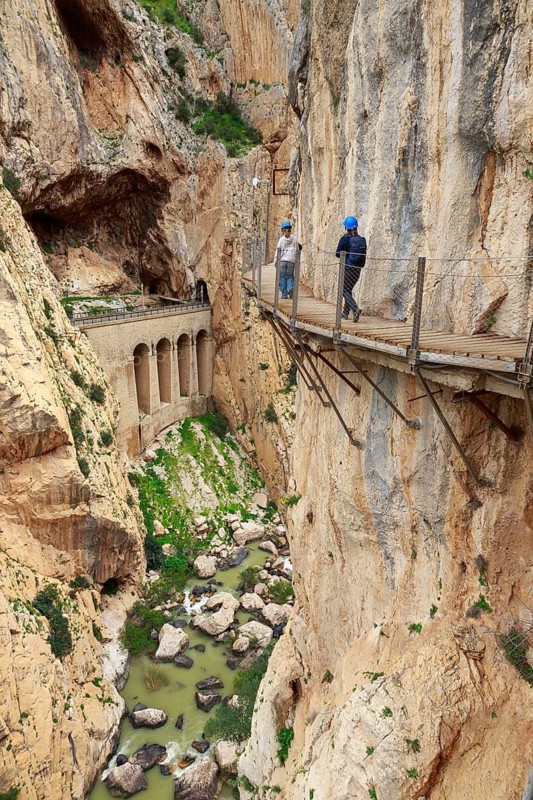 Two hikers on a narrow bridge over a gorge on the Caminito del Rey, Malaga, Spain