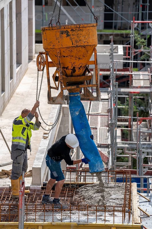 Construction site, concreting, concreting the balcony of a building, the concrete is pumped onto the reinforced concrete mats, spreading the concrete