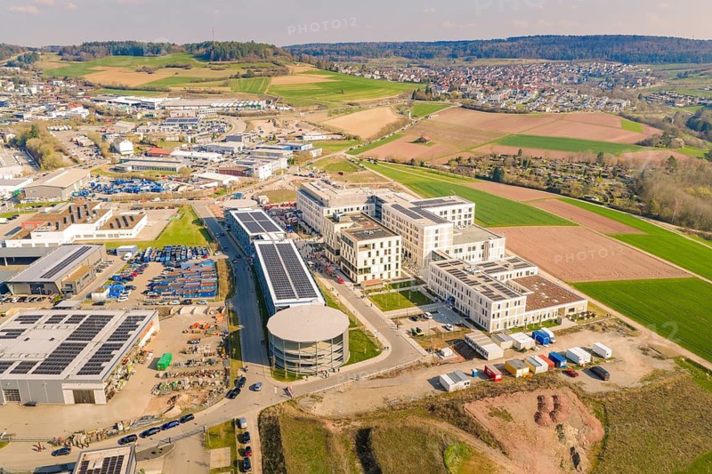 Industrial area with solar systems and modern buildings, surrounded by rural and urban landscape, new hospital at the Verbund Südwest Clinic, Calw, Germany