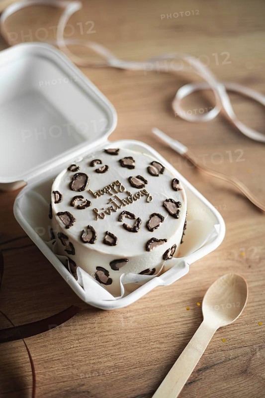 Charming mini birthday cake with a trendy leopard print theme enclosed in a white takeout box, perfect for a special occasion gift