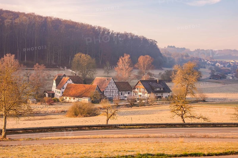 Idyllic village landscape with half-timbered houses and wooded hills in morning sunlight, Gechingen, Calw district, Germany