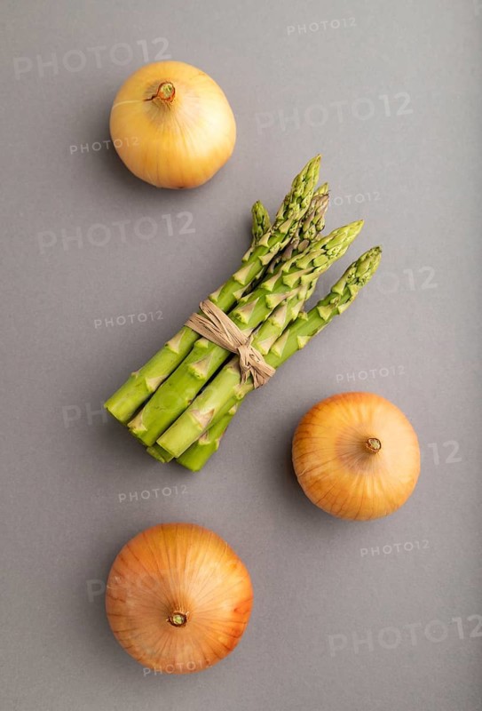 Bunch of fresh green asparagus and onion on gray pastel background. Top view, flat lay, close up. harvest, healthy, vegan food, concept, minimalism