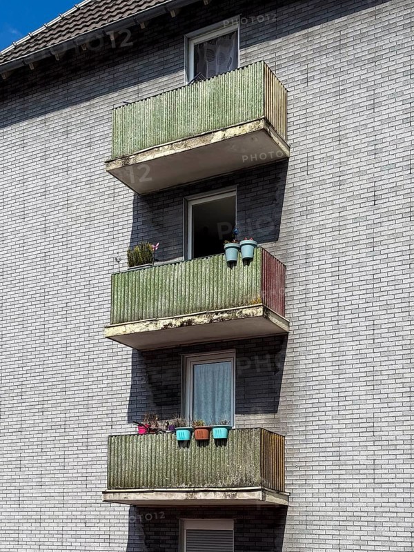 Balconies with privacy screens and colourful flower boxes on a house with grey clinker brick in Wuppertal, Germany