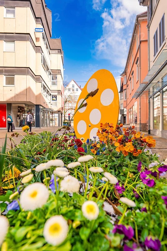 Springtime floral decoration with orange egg in a busy urban environment, Nagold, Calw district, Germany