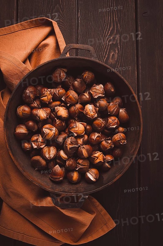 Roasted chestnuts, in an iron pan, wooden table, top view, no people, rustic style