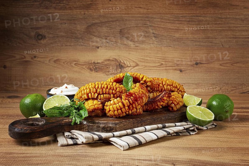 Corn ribs, with cream sauce, spices and lime, appetizer, on a wooden cutting board, homemade, no people