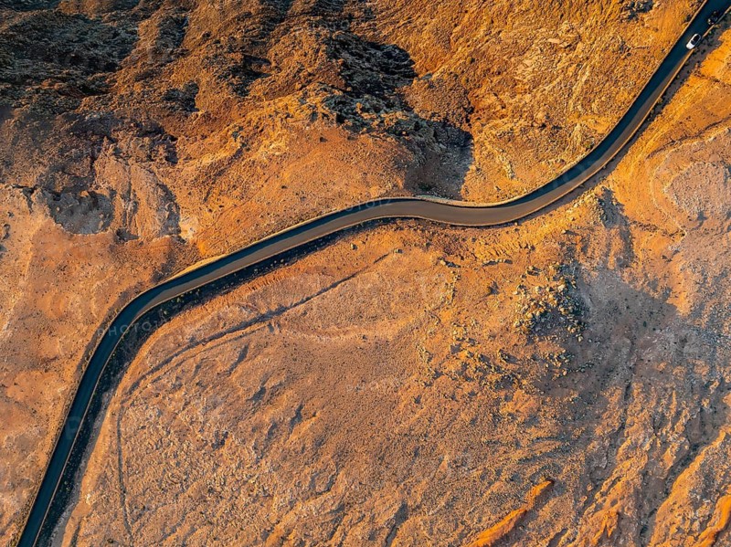 Road on cliffs through dry landscape in evening light, top-down shot, near Mirador del Porrito, aerial view, at sunset, Lanzarote, Canary Islands, Spain