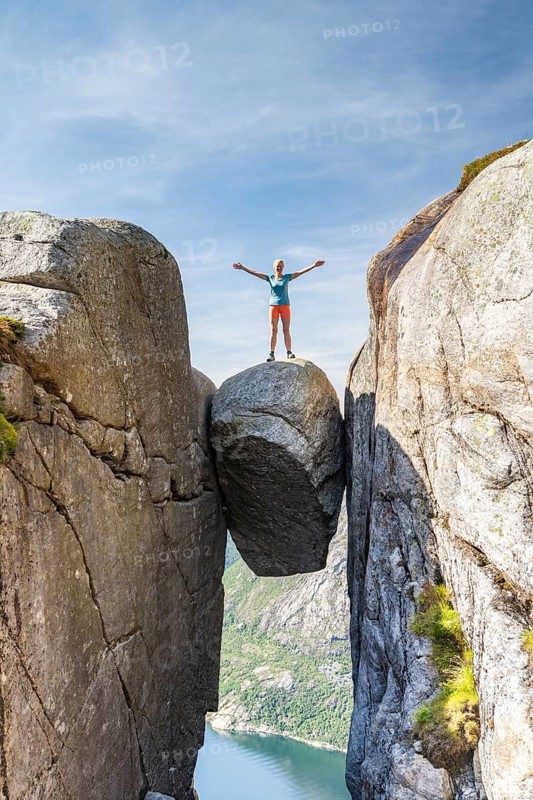 Woman standing onKjeragbolten, jammed rock above the Lysefjord, Kjerag, Lysebotn, Rogaland, Norway