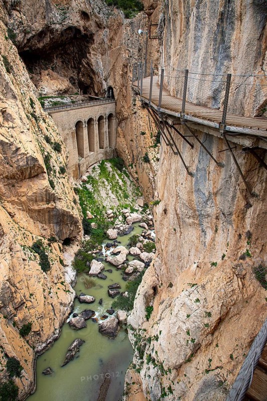 A path on a bridge leads over a rocky gorge with a river on the Caminito del Rey trail, Malaga Spain Europe