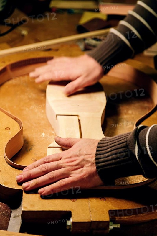 A luthier skillfully shapes components in a bass guitar workshop, demonstrating precision and craftsmanship. This image captures the essence of handmade musical instrument creation