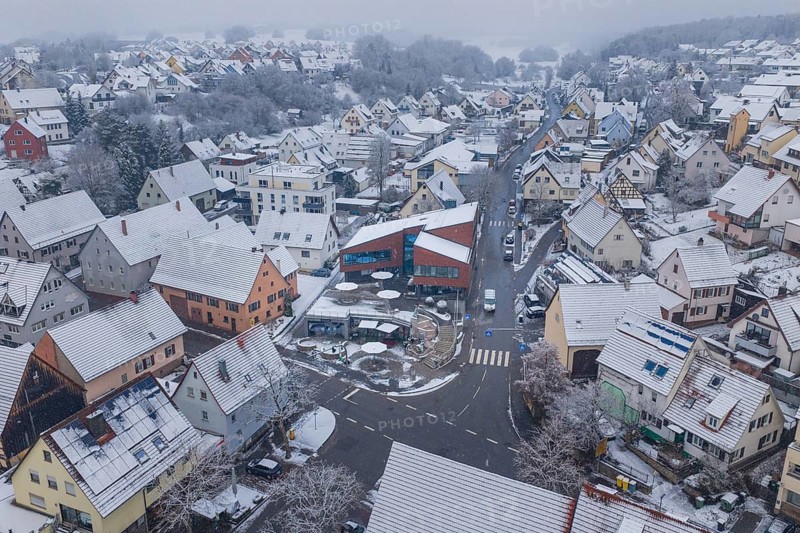 Panoramic view of a snowy village with many houses and roads in a foggy winter landscape, Gechingen Town Hall, Germany