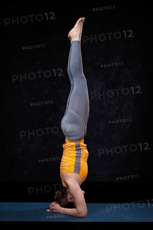 Yoga, woman doing Ashtanga Vinyasa Yoga asana sirsasana, headstand exercise on black grunge background