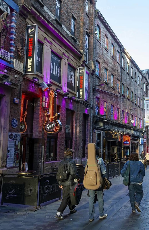 Men walking past with guitars, Eric's music club, Mathew Street, Liverpool, Merseyside, England, UK