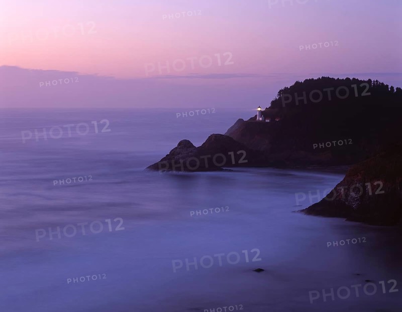 Soft violet hues of twilight bathe Heceta Head Lighthouse on the rugged Oregon Coast, casting a serene glow over the Pacific Ocean