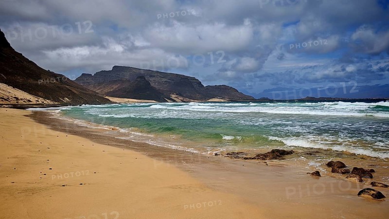 Remote, secluded sandy beach by the sea with waves and mountains in the background under cloudy sky, hiking Calhau, Baia das Gatas, Sao Vicente, Cabo Verde, Cape Verde, Cape Verde