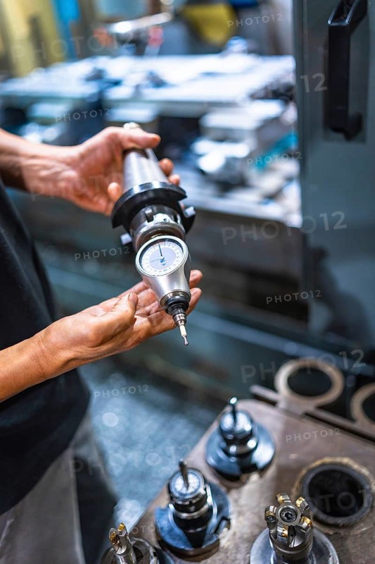 Vertical close-up of an unrecognizable caucasian male technician holding a piece of milling machine working in the factory