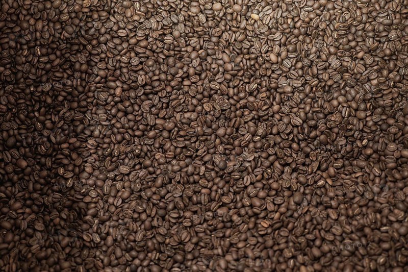 A close-up view of a large pile of freshly roasted coffee beans, highlighting their rich color and texture. Ideal for artisanal brewing and specialty coffee shops