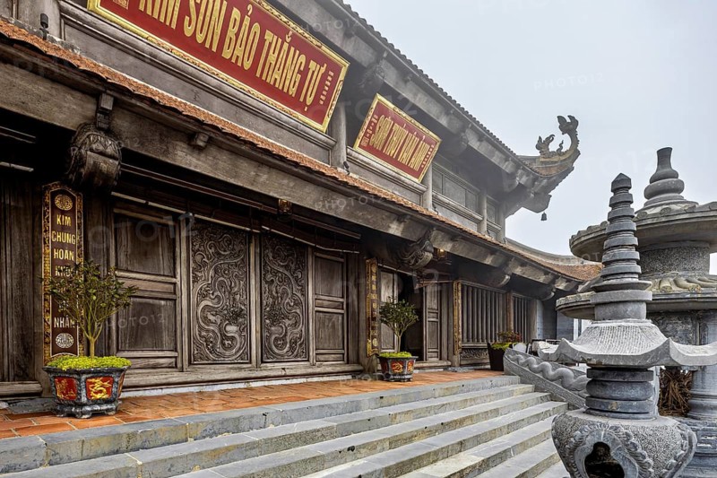 Detailed temple with wood carvings and plants on wide stone steps, The temple complex at Fansipan near Sa Pa in Vietnam