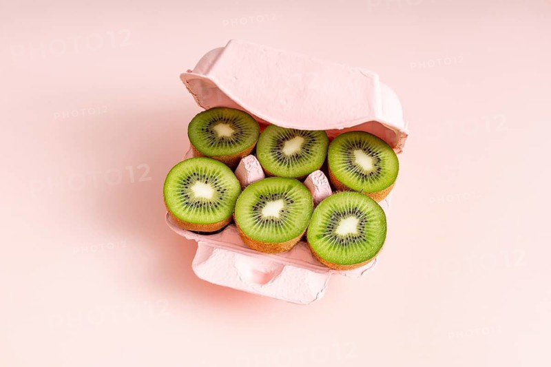 From above, fresh kiwi slices neatly arranged in a pink egg carton, suggesting a nutritious and creative alternative to traditional Easter eggs