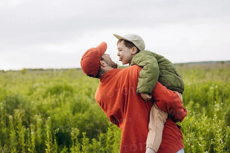 A dad and his young son enjoy a walk through a lush green field, creating joyful memories together. The scene captures the essence of a loving father son relationship