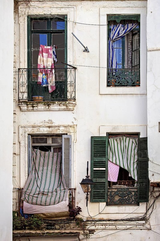 Dilapidated building with colourful cloths on the windows, gives a nostalgic urban charm, window in the old town of Algiers in Algeria