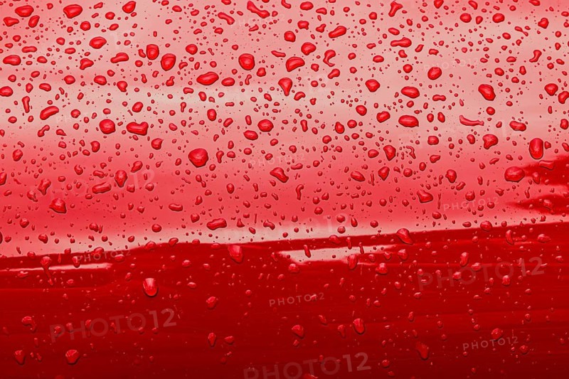 Abstract red background of wet metallic surface with raindrops