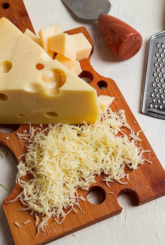 Grated cheese, Maasdam, on a cutting board, grater and cheese knife, close-up, no people