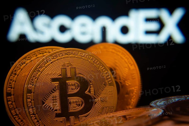 Dhaka, Bangladesh- 02 June 2025: Close-up of Bitcoin coins with the AscendEX logo visible on a screen in the background
