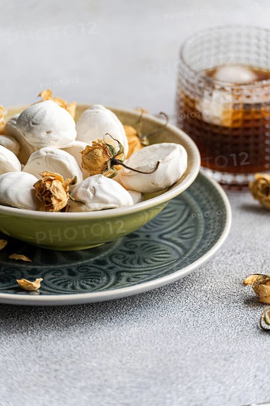 Homemade vanilla zephyr-marshmallows filled with rose jam, elegantly paired with a chilled coffee liqueur drink over ice, capturing sweet indulgence and aromatic flavors