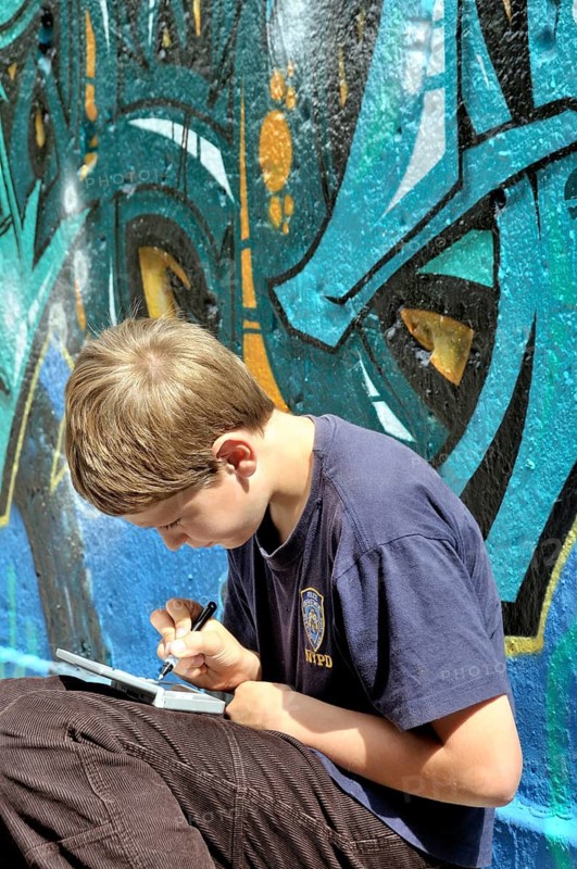 Ten-year-old boy playing with his Nintendo in front of a graffiti wall, football pitch, Germany