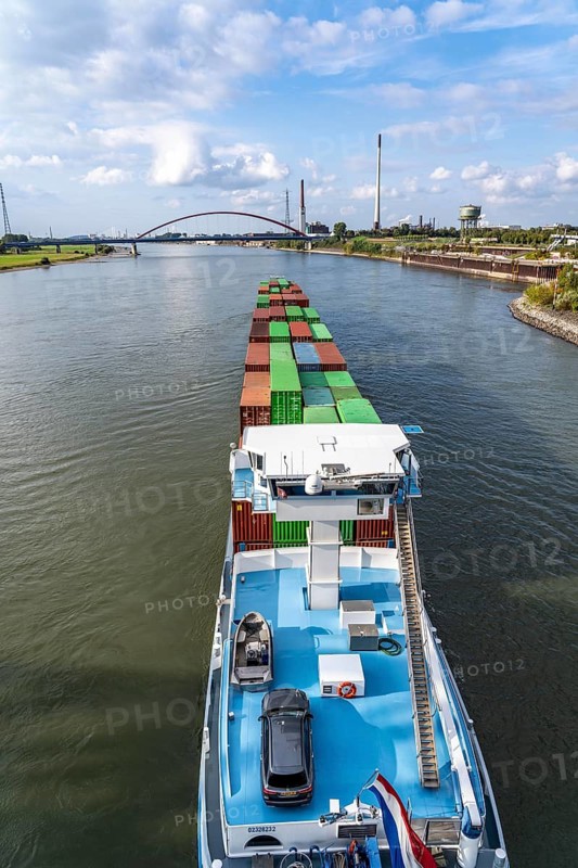 The Dutch cargo ship Vrido, loaded with containers, on the Rhine near Duisburg, descending, behind the so-called bridge of solidarity over the Rhine, near Duisburg-Rheinhausen, North Rhine-Westphalia, Germany