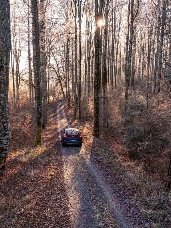 Car driving along a forest path, surrounded by tall trees and autumn leaves, Car Sharing, Electric car, Volkswagen ID 5, Gechingen, Hecken und Gäu Region, Black Forest, Germany
