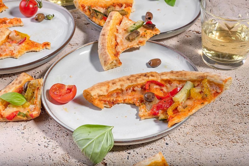 Slices of mouthwatering vegetarian pizza topped with vibrant bell peppers, ripe tomatoes, and fresh basil on a crispy crust, ideal for a tasty and healthy meal