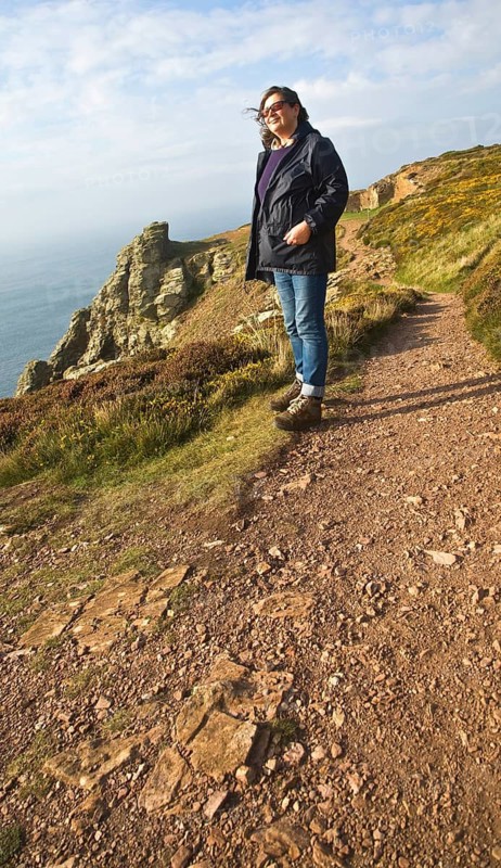 Woman wearing kagoule walking along the South West coast path at St Agnes head, Cornwall, England, United Kingdom