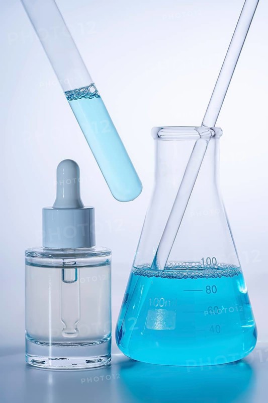Laboratory setup featuring a dropper bottle, test tube, and beaker filled with vibrant blue liquid, showcasing a scientific and experimental atmosphere