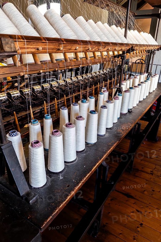 Bramsche, Lower Saxony, Germany, rows of yarn bobbins on an old machine in a textile factory, clothmaking museum