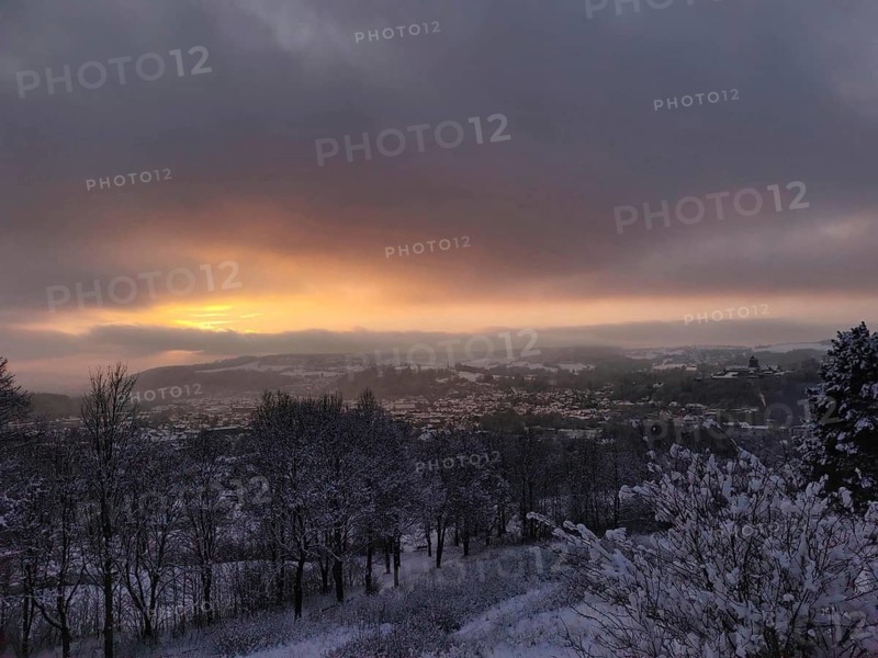 Snowy landscape at sunset with view of Rosenberg Kronach Fortress, Frankenwald nature park Park