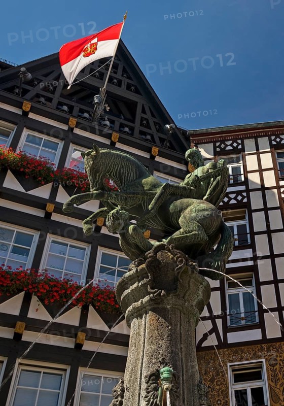 Fountain on the market square with half-timbered houses and flag with town coat of arms, Cochem, Rhineland-Palatinate, Germany