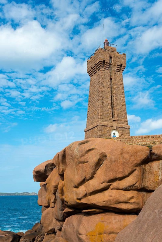 Stony lighthouse rises above the rocks under a clear sky, Phare de Men Ruz, Ploumanac'h, Ploumanach, Pointe de Squewel, Perros-Guirec, pink granite coast, Côte de Granit Rose, Brittany, France