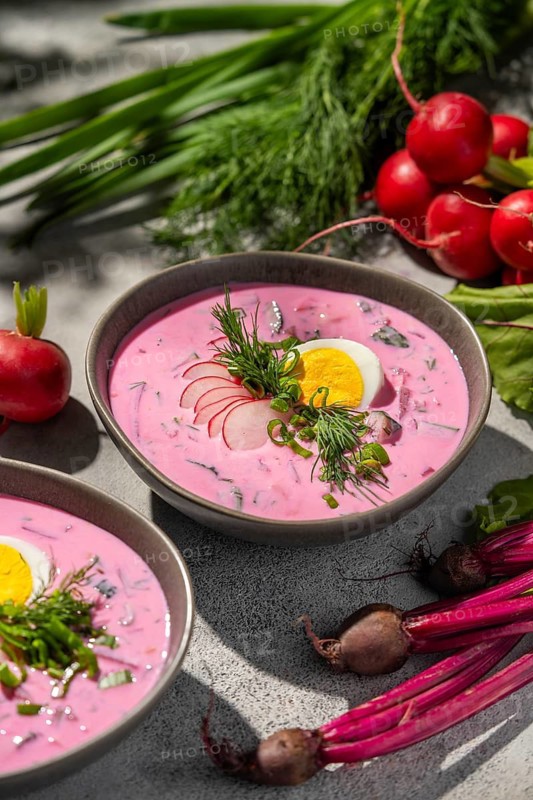 A refreshing bowl of cold beetroot soup served with sliced radishes, hard-boiled eggs, and fresh dill. This vibrant dish showcases a fusion of flavors, perfect for summer
