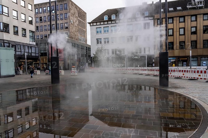 Digital water feature, Blue Cloud water installation on Husemanplatz in downtown Bochum, water mist is sprayed from 4 metal masts, which, in conjunction with the circular water surface, is intended to cool the surrounding area when it is hot, colored light images are projected into the water mist via projectors, part of the transformation of Husemanplatz