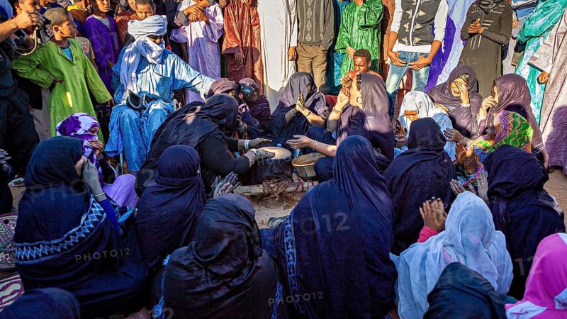 People in traditional dress at a cultural gathering, lively and communal, Traditional woman play music at the Tuareg Festival of Tamanrasset in the Sahara in Algeria