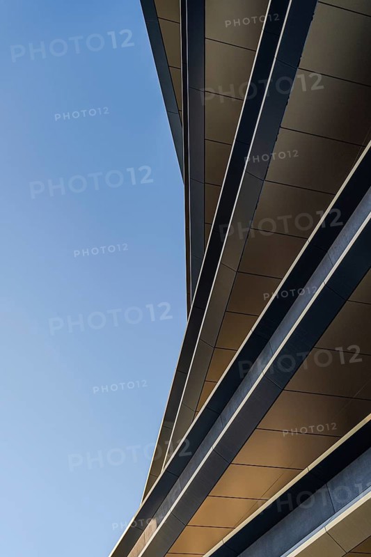 Capturing the sleek lines and sharp angles of modern architecture, this image showcases the intricate details of a contemporary building against a clear sky backdrop