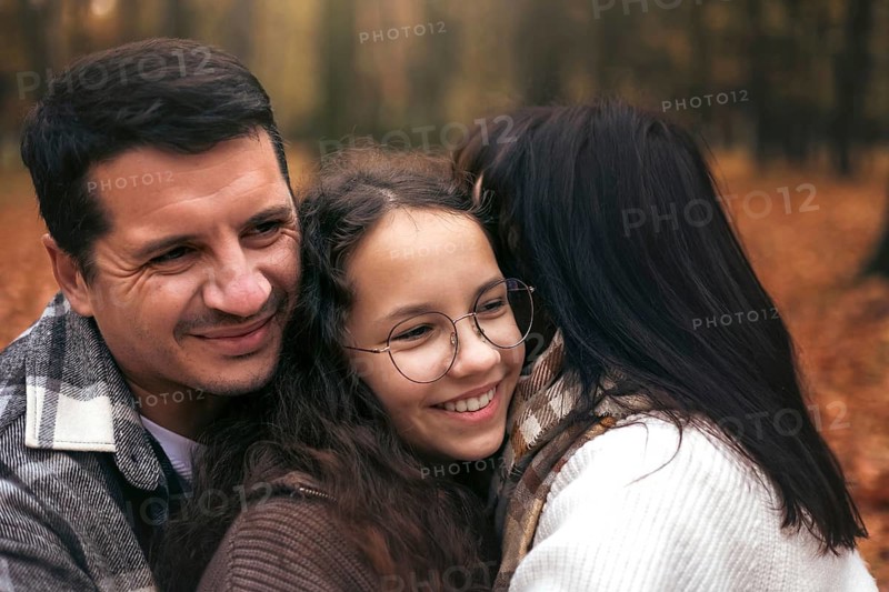 A family shares a joyful embrace surrounded by the warm hues of autumn foliage. The scene captures the essence of togetherness and the beauty of nature during the fall season